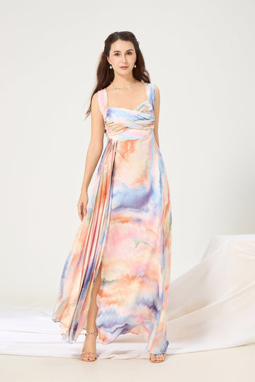 Woman wearing a Vanda Modes watercolor maxi dress with soft pleats and side slit, ideal for elegant evening events or summer weddings.